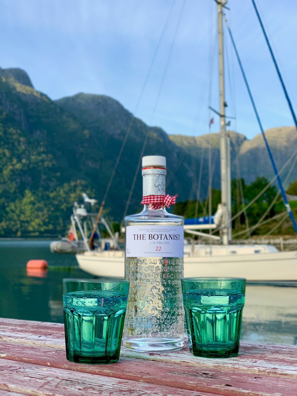 clear glass bottle beside green drinking glass