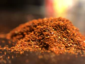 Macro shot of rich paprika powder swirling in golden light.