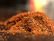 A vibrant heap of deep red paprika powder spilling gently onto a charcoal background.