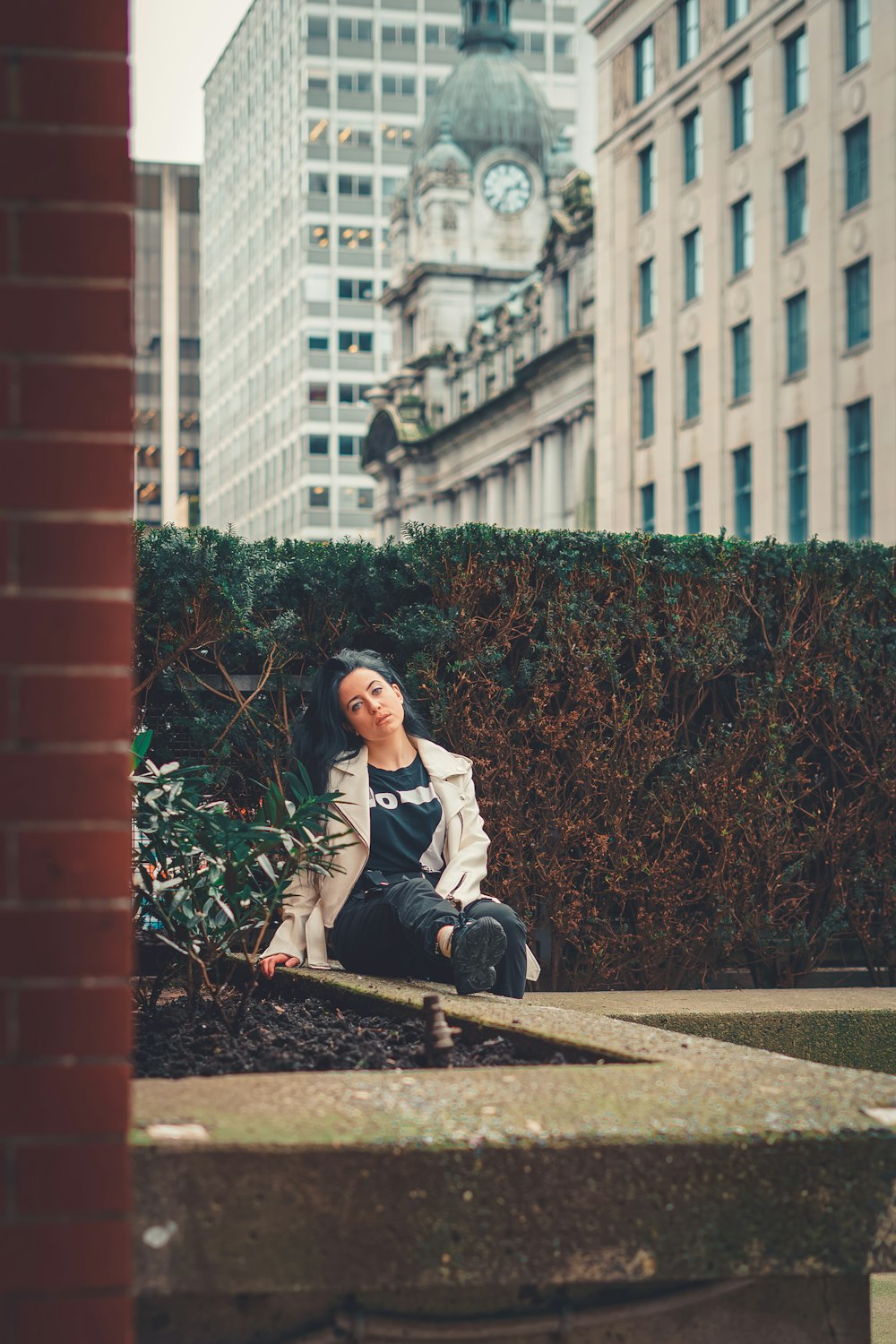 woman in white long sleeve shirt sitting on brown concrete bench during daytime