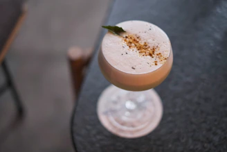 Close-up of a frosty frappé cocktail garnished with fresh herbs and citrus slices.