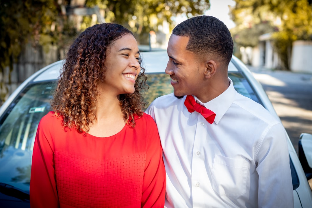 man in white dress shirt beside woman in red tank top