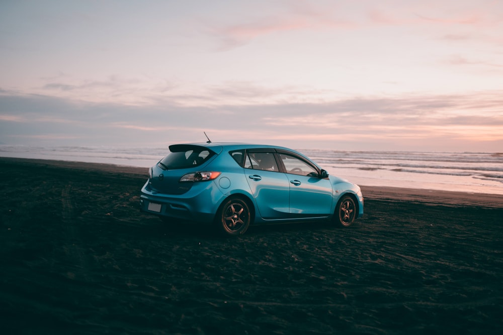 Volkswagen Coccinelle bleue sur le rivage de la plage pendant la journée