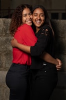 woman in red shirt hugging woman in black shirt