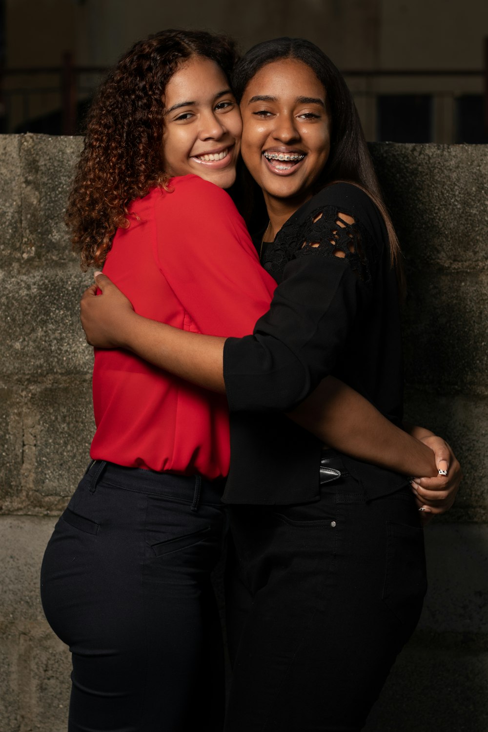 woman in red shirt hugging woman in black shirt