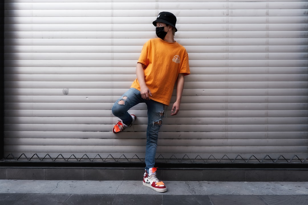 man in orange crew neck t-shirt and blue denim jeans standing on black and white