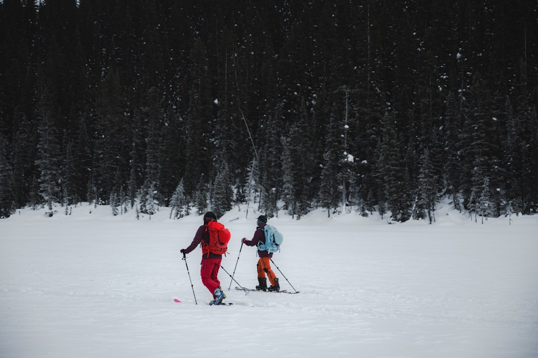 person in red jacket and black pants riding ski blades on snow covered ground during daytime
