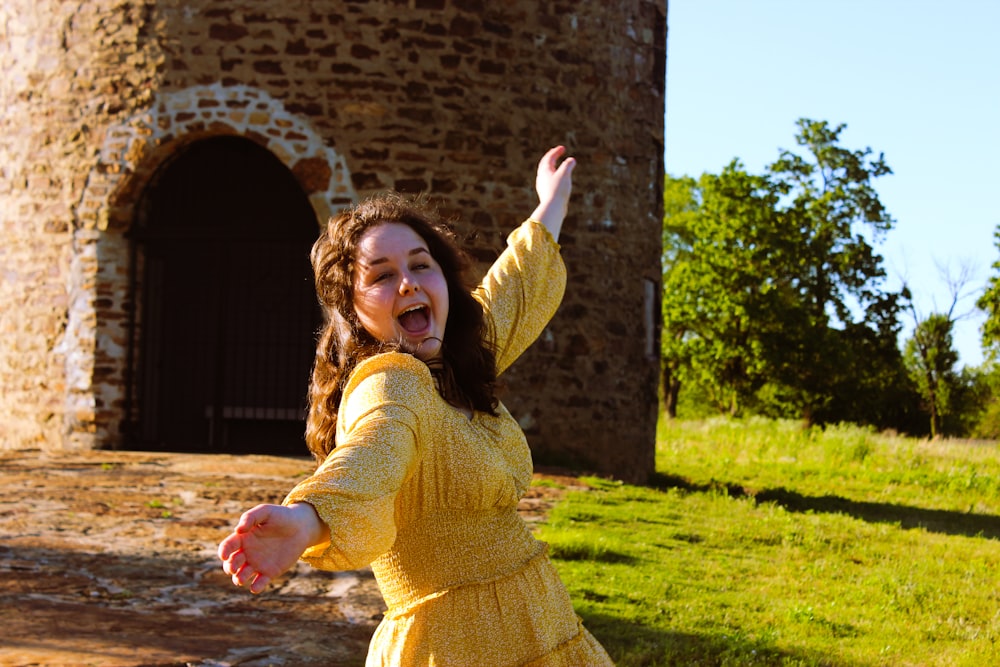 girl in yellow long sleeve dress standing on green grass field during daytime