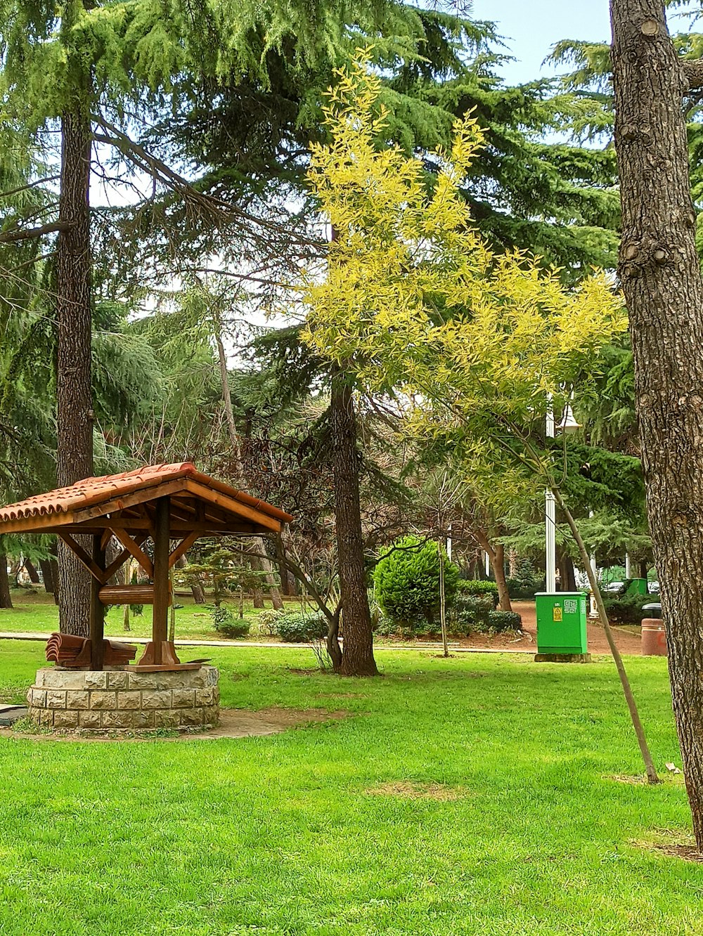 brown wooden gazebo in the middle of green grass field