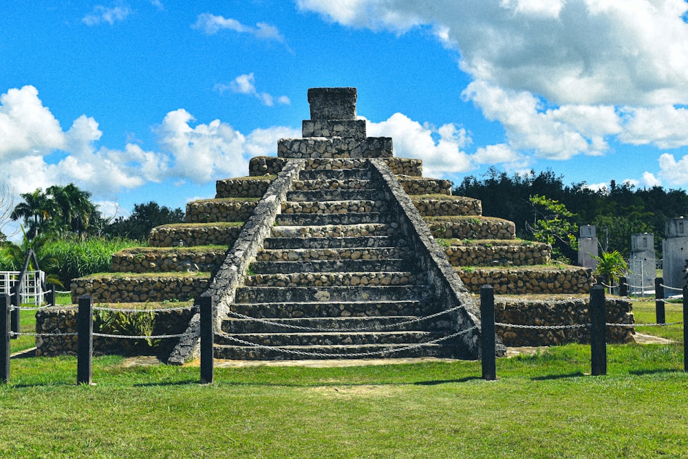 gray concrete stairs on green grass field under blue sky during daytime