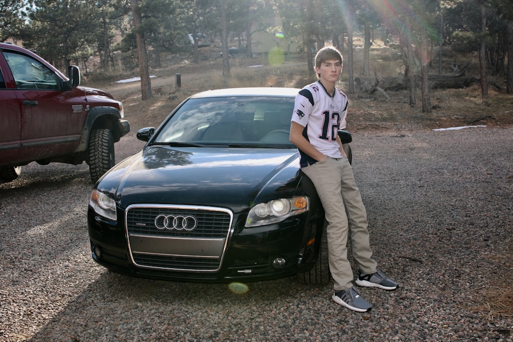 man in blue and white stripe polo shirt leaning on black mercedes benz car