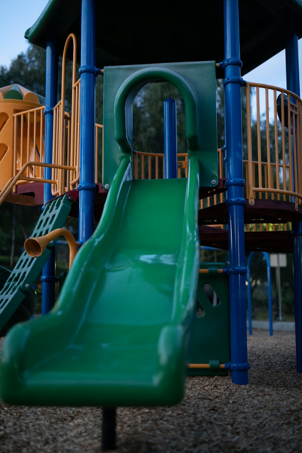 green plastic slide near brown metal fence