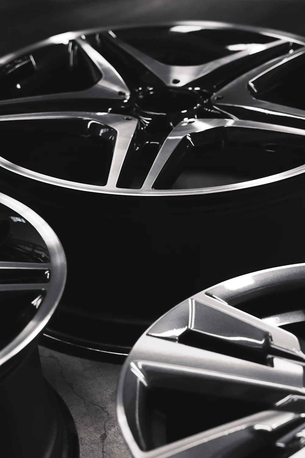 Stacked black multi-spoke alloy wheels in a studio