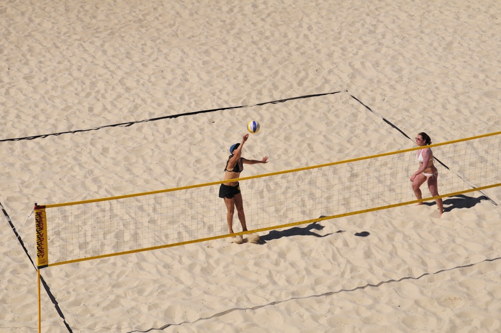 woman in black bikini holding yellow and white volleyball