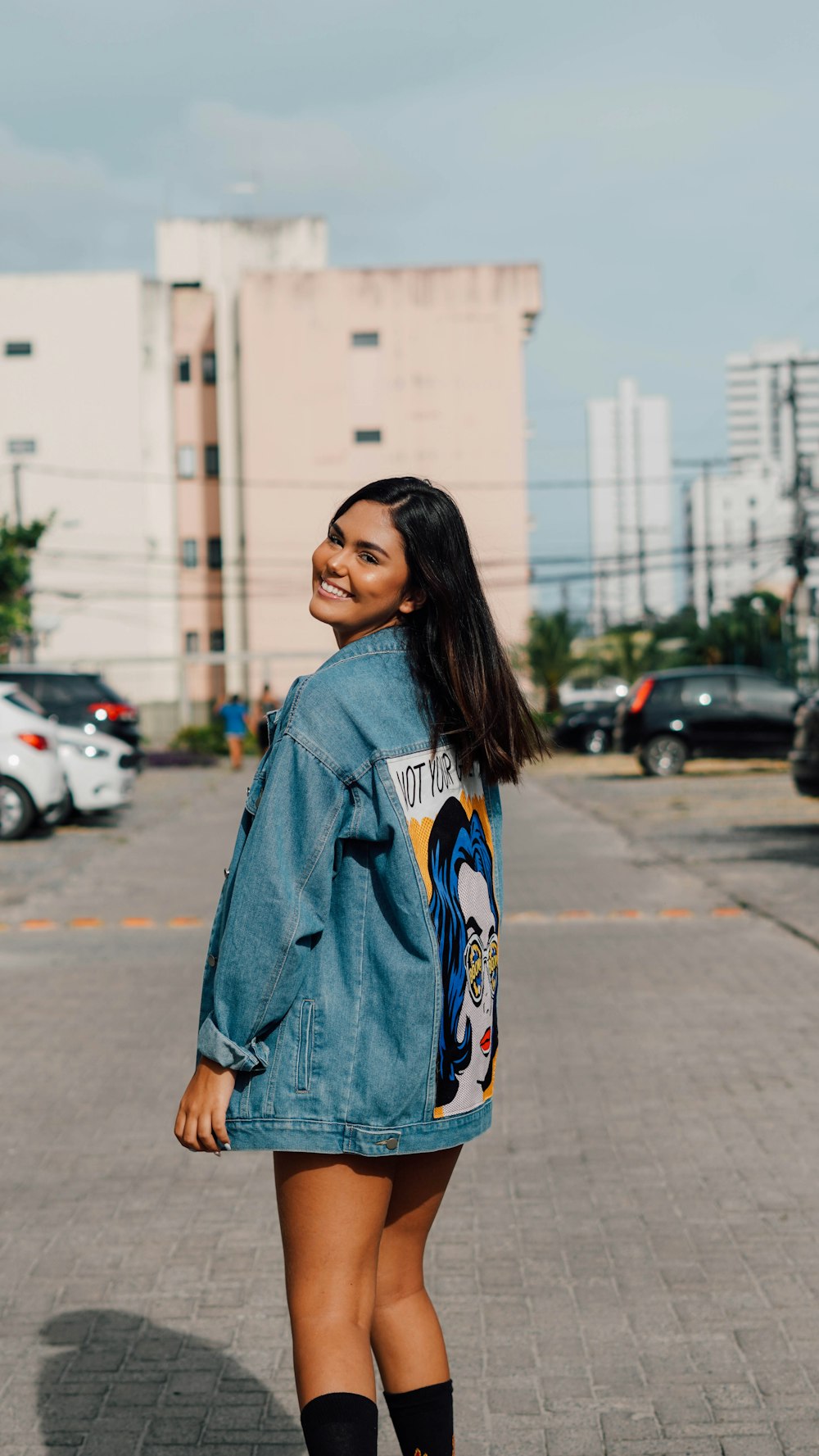 woman in blue and white hoodie standing on sidewalk during daytime