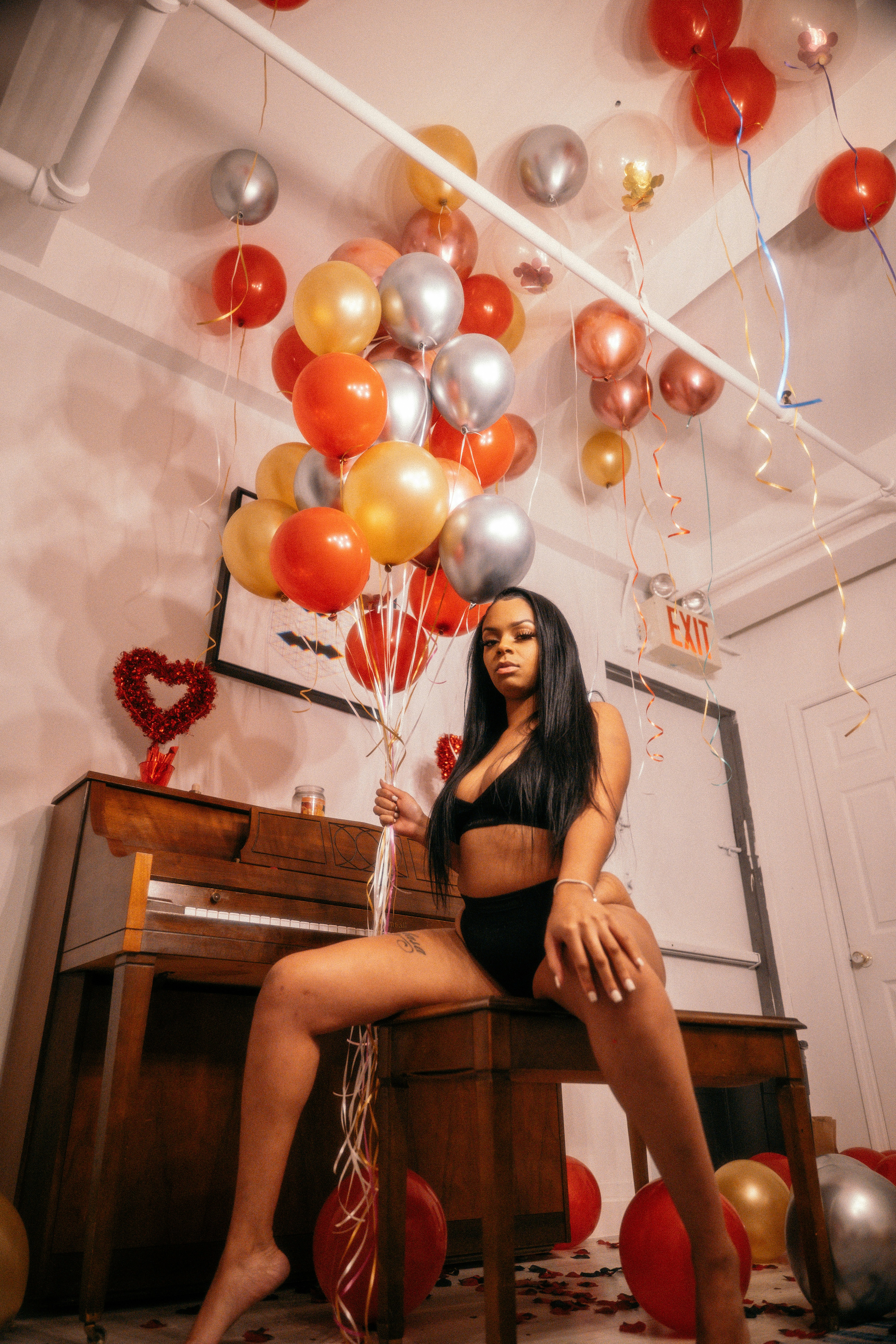 woman in black crop top and black skirt holding balloons