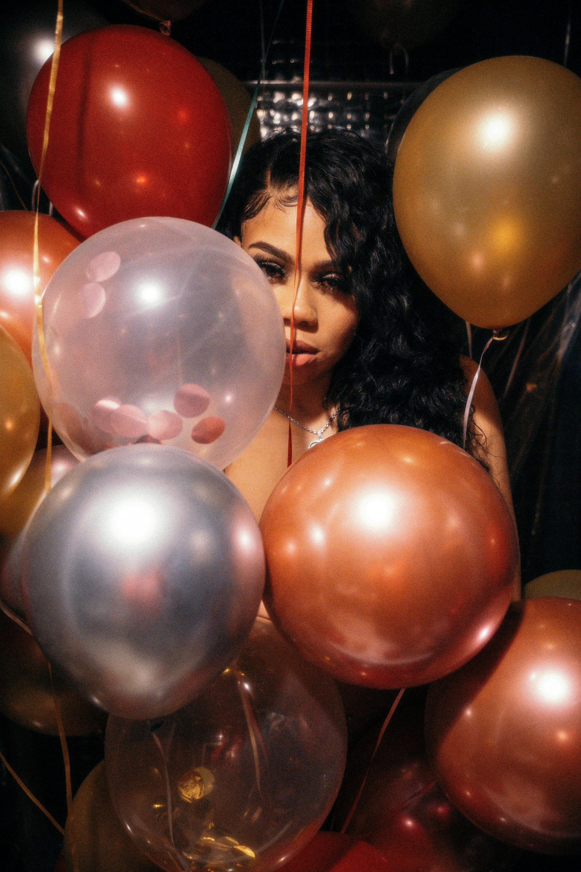 woman in black shirt standing beside red and gold balloons