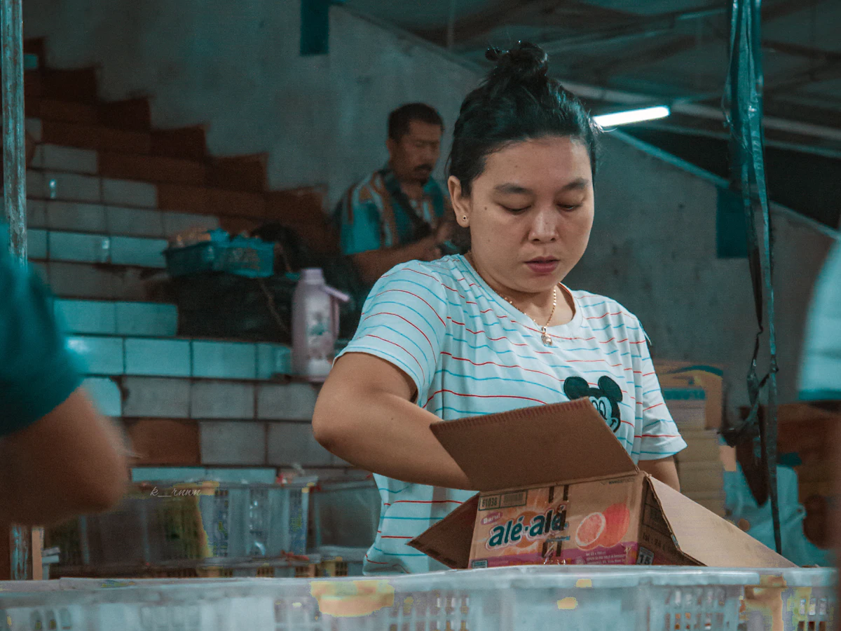 Perempuan memegang kotak kardus paket di meja pengemasan
