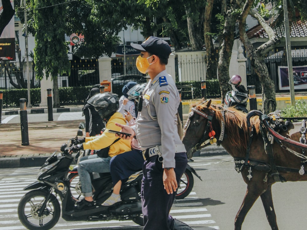 man in white jacket riding on black horse during daytime