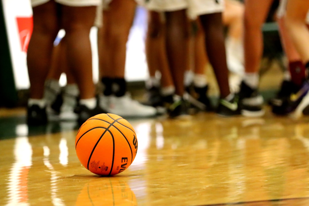 orange basketball on brown wooden floor, Basketball lies on the court during a high school basketball game time-out.