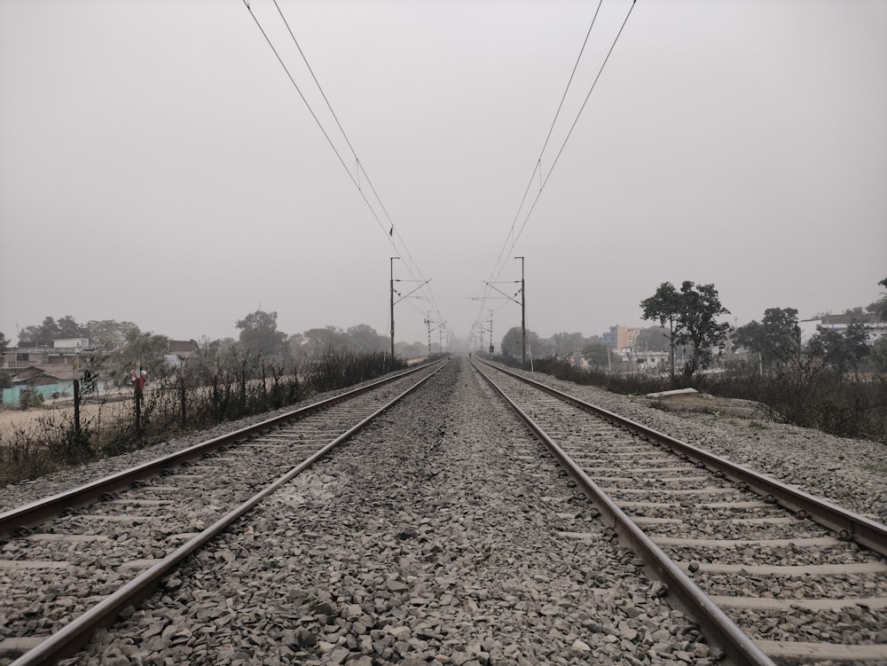 train rail tracks under white sky during daytime