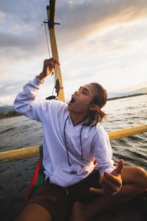 A beginner angler holding a small bass with a proud smile on a misty morning lake.