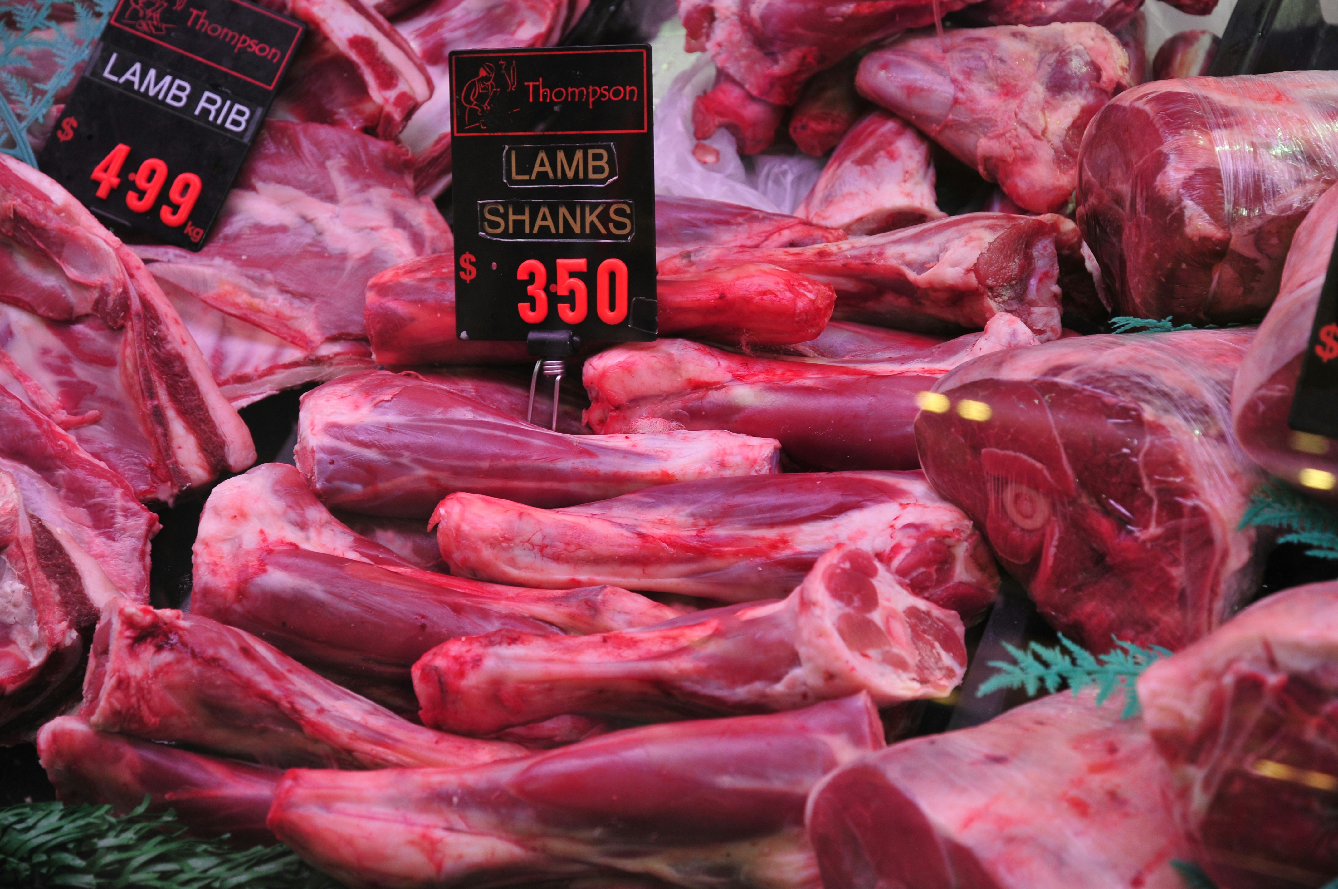 Fresh goat meat portions arranged on clean market counter, well-lit traditional butcher shop
