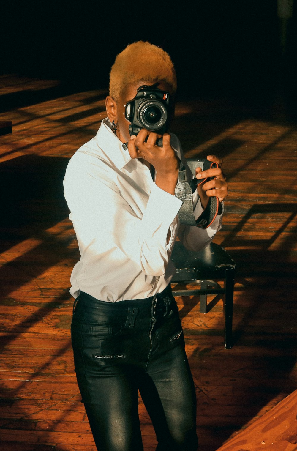 man in white long sleeve shirt and black denim jeans holding black dslr camera