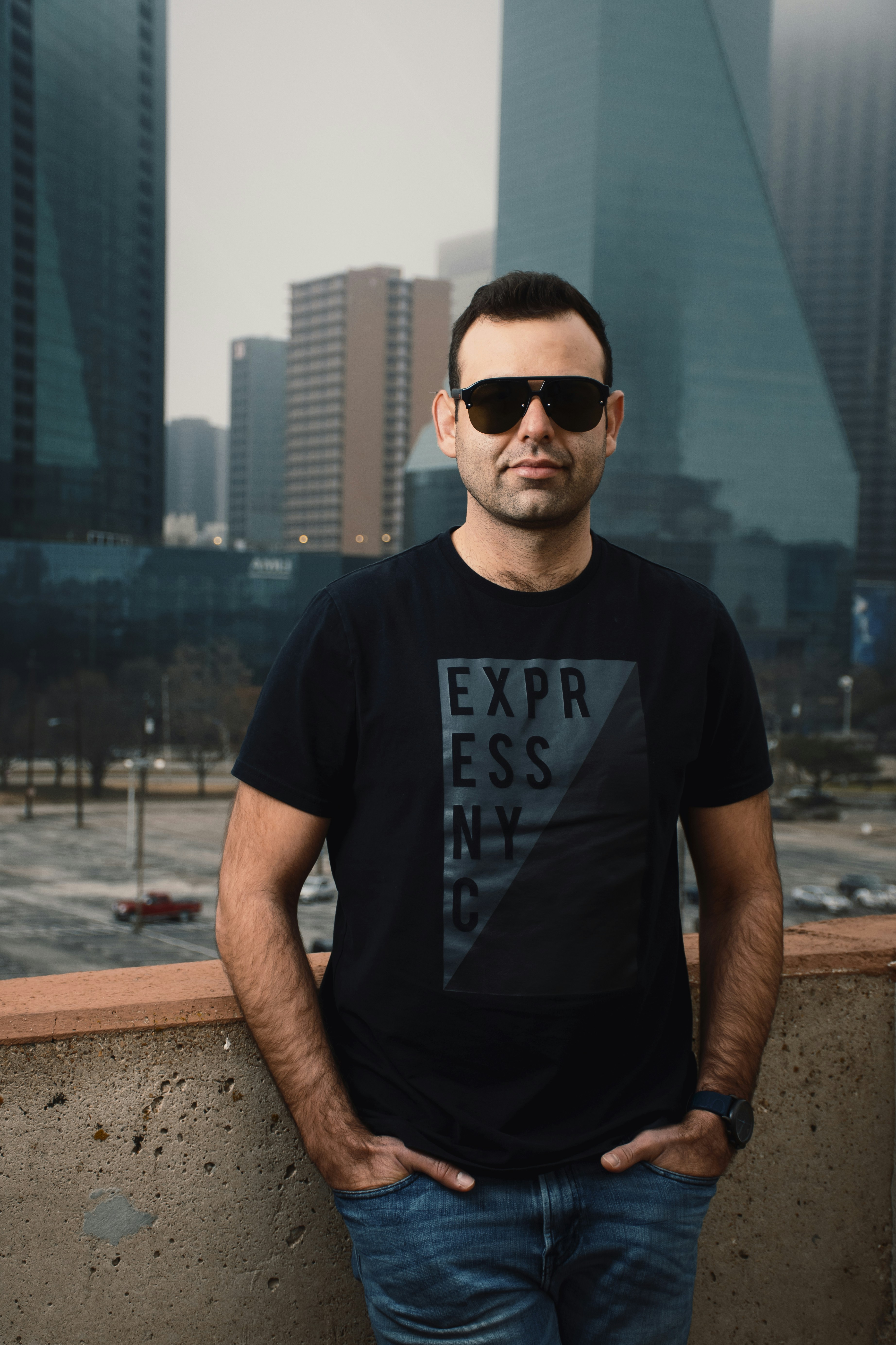 homme en t-shirt à col rond noir portant des lunettes de soleil noires debout près du plan d’eau pendant