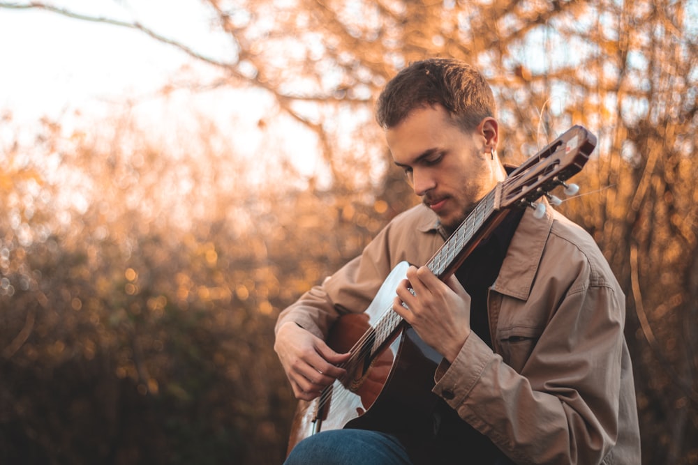 man in brown coat playing guitar