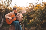 man in brown dress shirt playing acoustic guitar