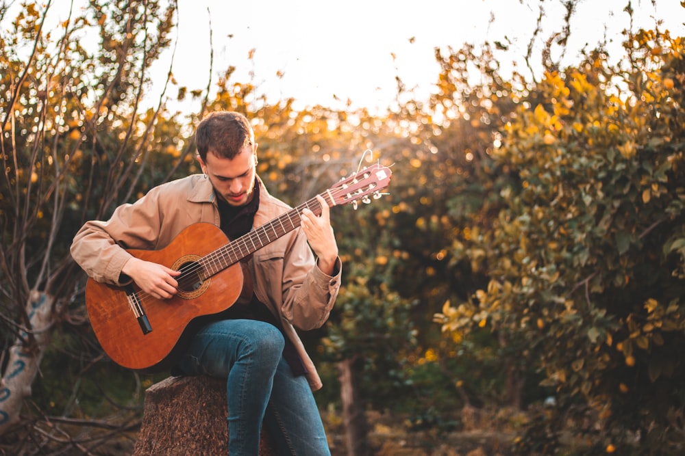 man in brown dress shirt playing acoustic guitar
