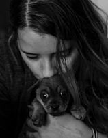 A volunteer gently holding a rescued puppy, both sharing a tender moment.