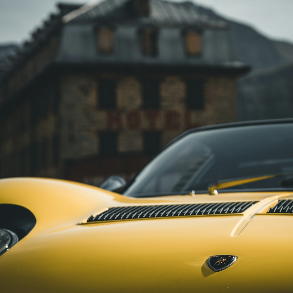 yellow porsche 911 parked near brown concrete building during daytime