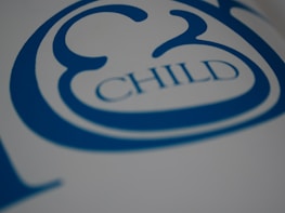 A close-up view of stylized blue text on a white surface, featuring the word 'CHILD' with decorative elements surrounding it.