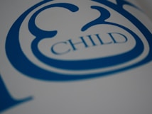 A close-up view of stylized blue text on a white surface, featuring the word 'CHILD' with decorative elements surrounding it.