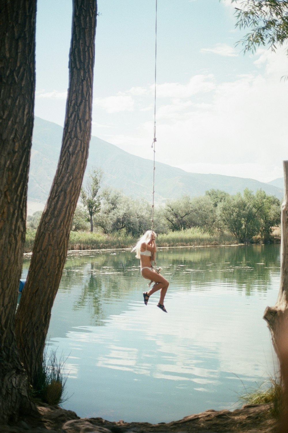 Mujer con camiseta blanca sin mangas y pantalones cortos negros saltando sobre el agua durante el día