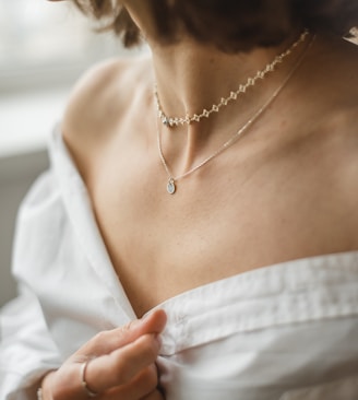 woman in white off shoulder shirt wearing silver necklace