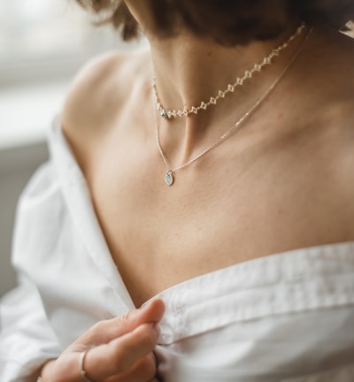 woman in white off shoulder shirt wearing silver necklace