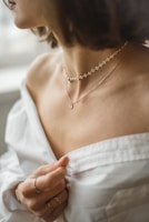 woman in white off shoulder shirt wearing silver necklace