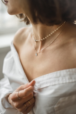 Woman wearing a delicate layered necklace with a casual chic outfit.