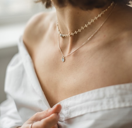 woman in white off shoulder shirt wearing silver necklace