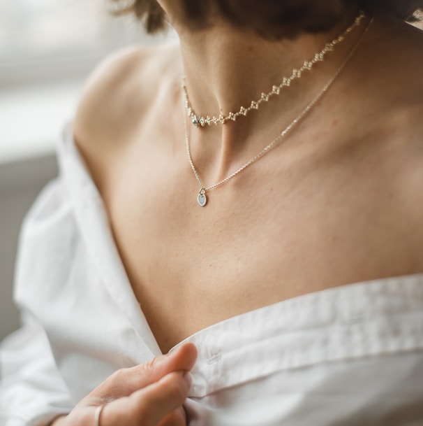 woman in white off shoulder shirt wearing silver necklace