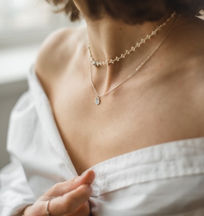 woman in white off shoulder shirt wearing silver necklace