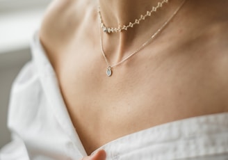 woman in white off shoulder shirt wearing silver necklace