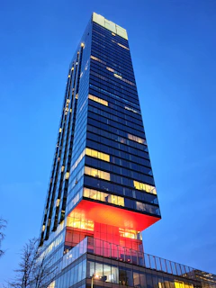 A sleek modern financial district building glowing with red accent lighting at dusk.