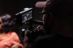 man in black hat holding black video camera