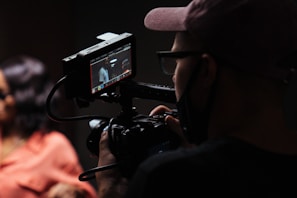 man in black hat holding black video camera