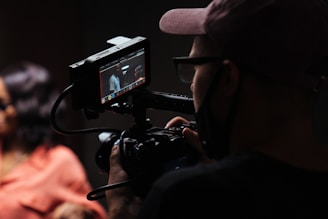 man in black hat holding black video camera