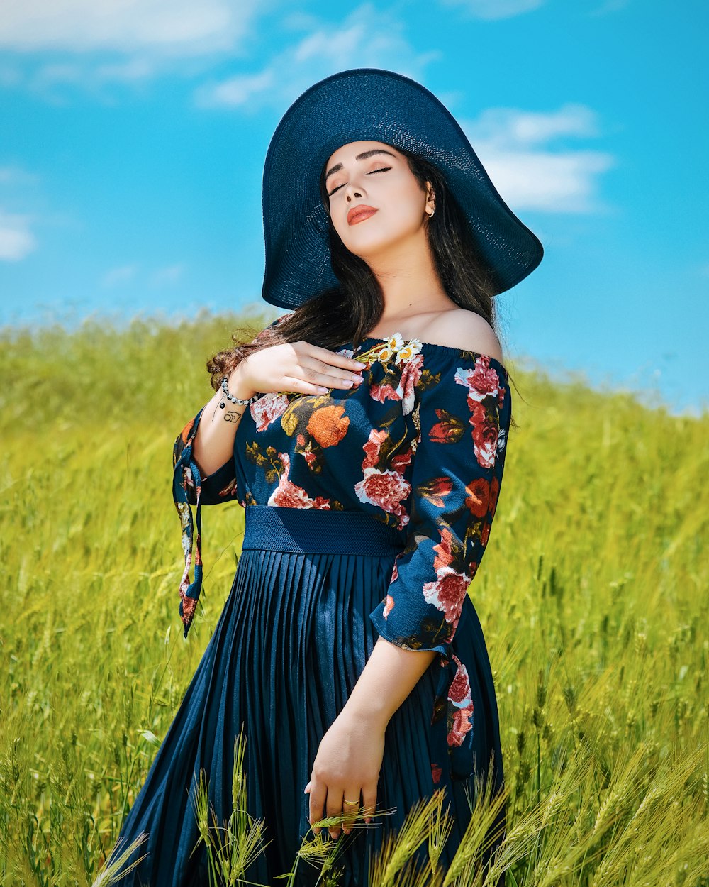 woman in black and yellow floral dress and black knit cap standing on green grass field